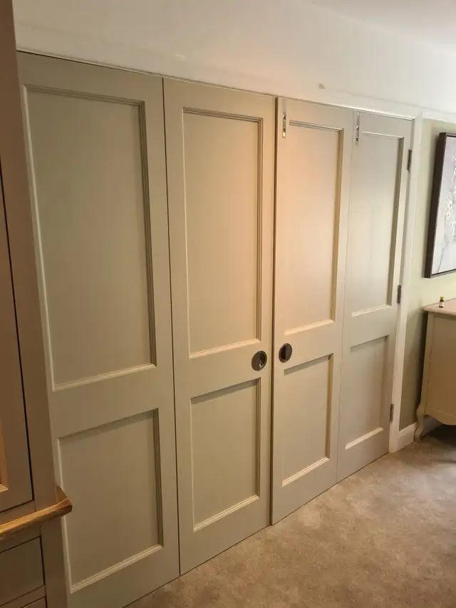 Sage painted panelled wardrobe doors in a bedroom