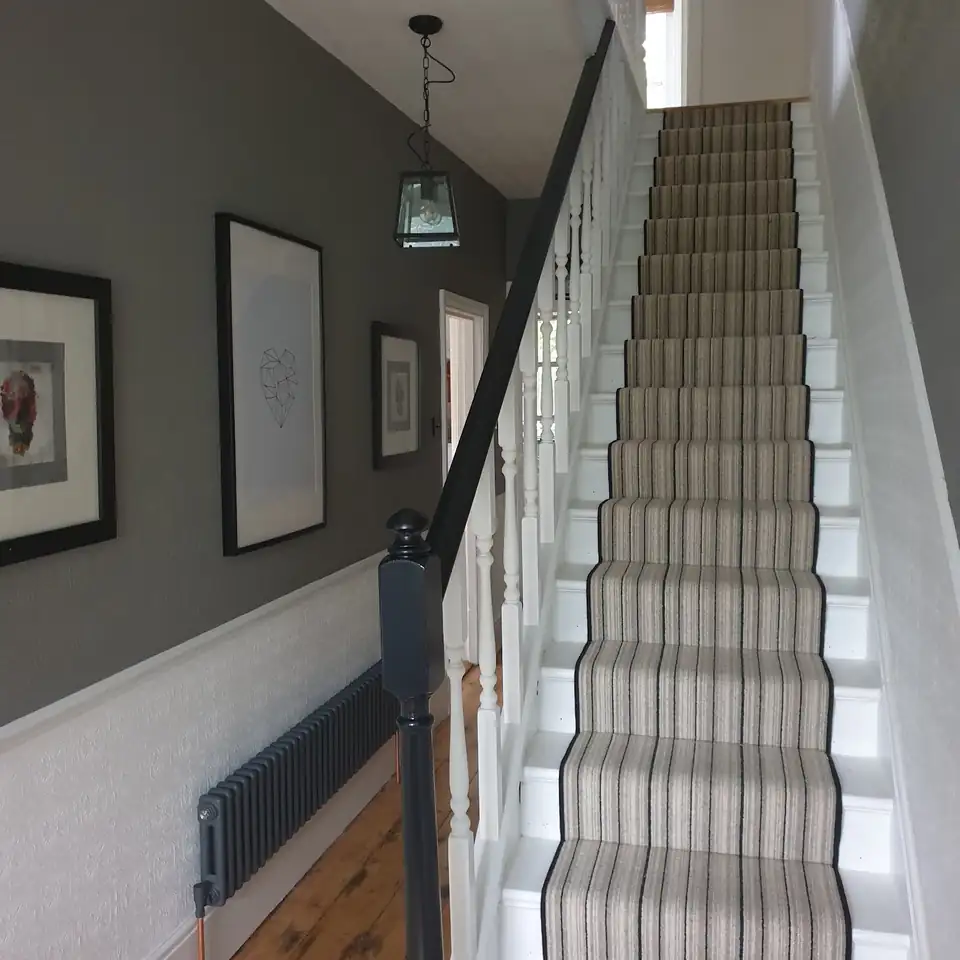 Grey hallway with white panelling and a striped stair runner, decorated by Sharp Decorating in Portslade